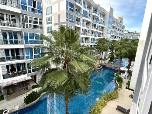 a palm tree in front of a building with a swimming pool at Grand Avenue Residence condominium in Pattaya