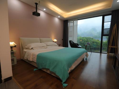 a bedroom with a bed and a large window at Zhangjiajie Southgate Flower Garden Lodge at the Park Entrance in Zhangjiajie