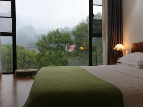 a bedroom with a bed and a large window at Zhangjiajie Southgate Flower Garden Lodge at the Park Entrance in Zhangjiajie