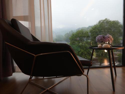 a chair and a table in a room with a window at Zhangjiajie Southgate Flower Garden Lodge at the Park Entrance in Zhangjiajie