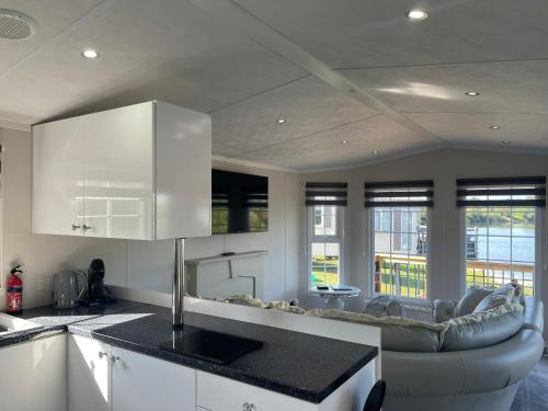 a kitchen and living room with white cabinets and a couch at Riverside Lodge, with Hot tub on The River Severn in Tirley