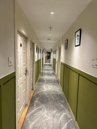 a hallway with green and white doors and a long aisle at Hotel Royal Palm Inn in Faizābād