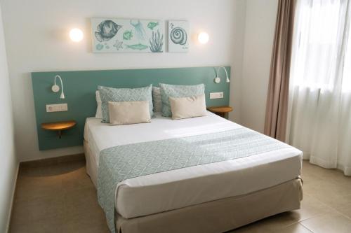 a bedroom with a large bed with a blue headboard at Pierre & Vacances Menorca Cala Blanes in Cala en Blanes