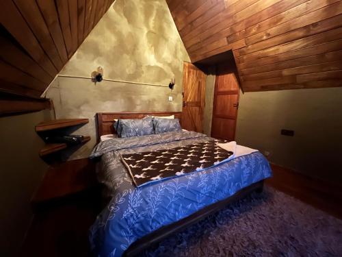 a bedroom with a bed with blue sheets and wooden ceilings at Rustique Lodge in Nuwara Eliya