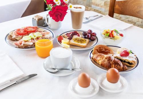 a table topped with plates of breakfast foods and drinks at Hotel Mary Rose in Lazise