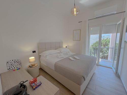 a white bedroom with a large bed and a window at Atsiki's 89 Apartments in Chios