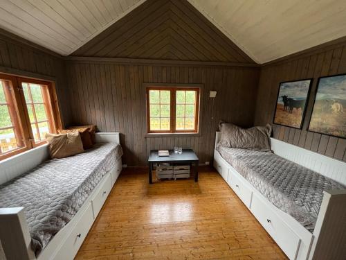 a room with two beds and a table in it at Koselig hytte på hugastølen in Vang I Valdres
