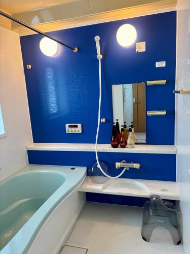 a bathroom with a tub and a blue wall at 一棟貸別荘Seaside Villa! 最大12名 弓ヶ浜海水浴場徒歩5分!ペット可 in Minamiizu