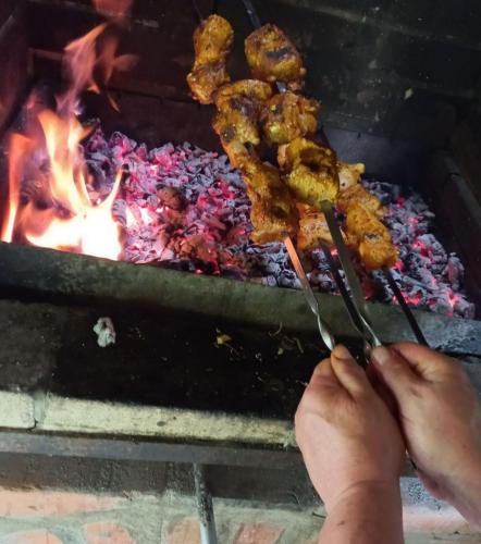 a person holding tongs in front of a grill at Дом с сауной и басейном на Теремках in Hatne