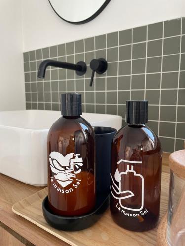 two bottles of soap sitting on a counter in a bathroom at la maison Sel in Audresselles
