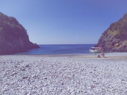 a boat on a beach with a rocky shore at Macondo in Abatemarco