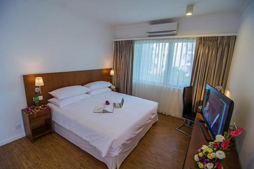 a hotel room with a large bed and a television at Sakura Residence & Hotel in Yangon