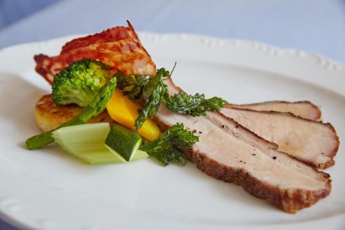 a white plate of food with meat and broccoli at Zum Fischer am See ***S in Prien am Chiemsee