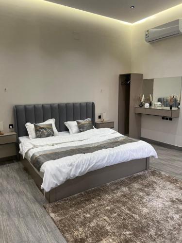 a bedroom with a large bed with a gray headboard at شاليه لدن in Hail