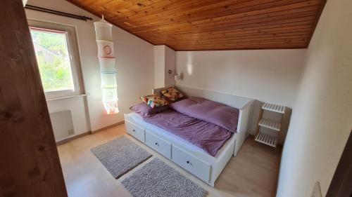 a bedroom with a bed with purple sheets and a window at Süße Doppelhaushälfte, mit Garten und Parkplätzen in Bouveret