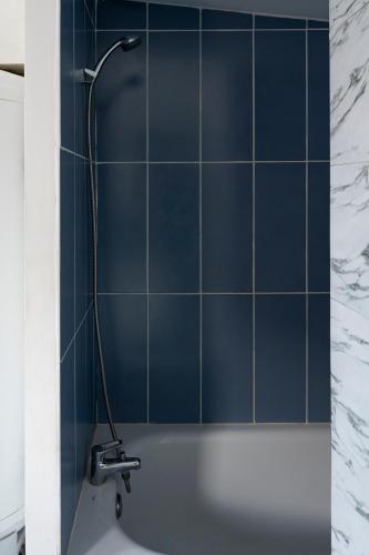 La salle de bains est pourvue de carrelage bleu, d'une douche et d'une baignoire. dans l'établissement L'Escapade Mirabeau - Confort à 4 & animaux ok, à Hénin-Beaumont