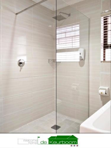 a shower with a glass door in a bathroom at De Keurboom Guesthouse in Kuilsrivier