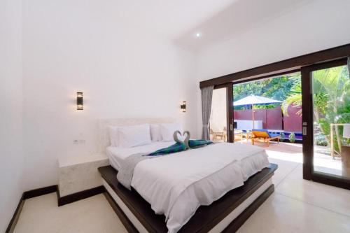 a bedroom with a large bed and a sliding glass door at Villa Kamaria in Gili Air