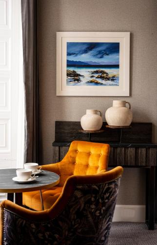 a dining room with a table and a yellow chair at Skeabost House Hotel in Portree