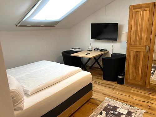 a bedroom with a bed and a desk with a television at Zum Fischer am See ***S in Prien am Chiemsee