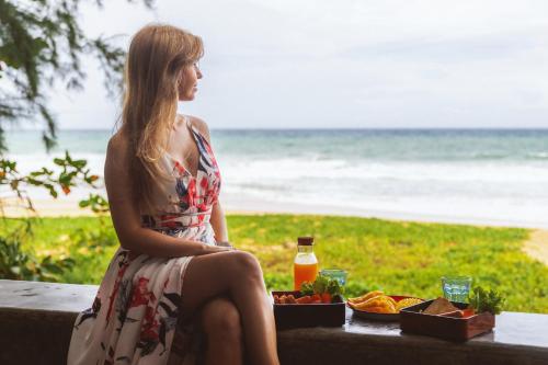 a woman sitting at a table with a tray of food at Sealord Naithon Beachfront Villa in Nai Thon Beach