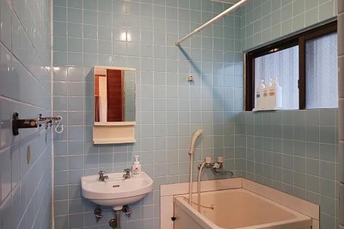 baño de azulejos azules con lavabo y bañera en パイナガマビーチハウス, en Isla Miyako
