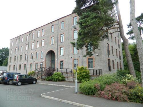 a large brick building with cars parked in front of it at The Mill Sixmilewater Mill Antrim in Antrim
