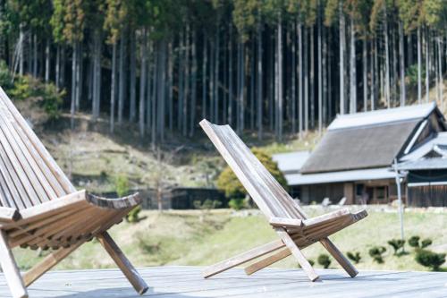 two wooden chairs sitting on top of a deck at うだ薬湯の宿やたきや in Uda