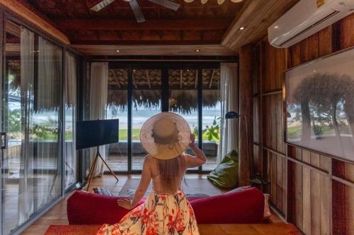 a woman wearing a hat sitting on a couch in a living room at Sealord Naithon Beachfront Villa in Nai Thon Beach