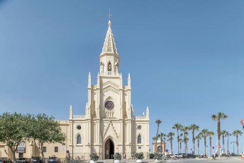 a church with a tower and a clock on the front at Apartamento Playa Regla in Chipiona