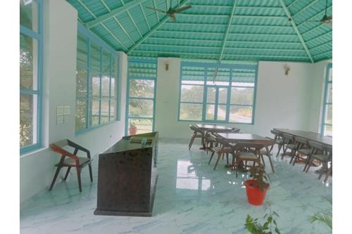 an empty room with tables and chairs and windows at Kumbhal Van Resort Unit of Chandraprabha in Kelwāra