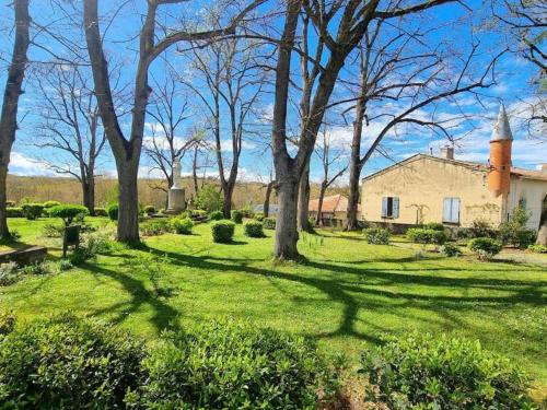 a yard with trees and a building with a tower at Petit coin de Paradis in Saint-Michel-de-Lanès