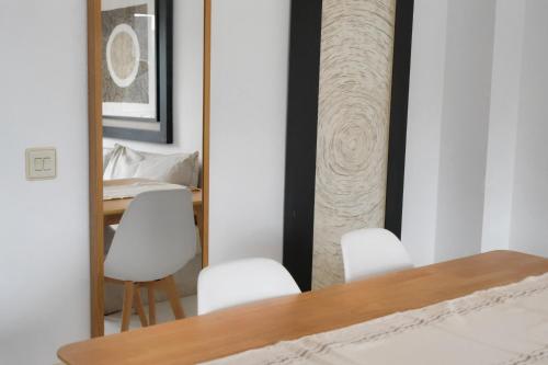 een eetkamer met witte stoelen en een spiegel bij Apartamento Marina Roses 4 in Roses
