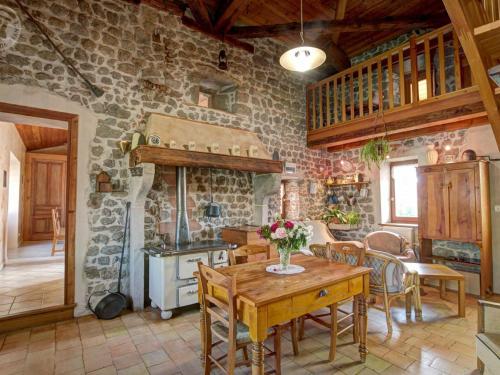 - une cuisine avec une table en bois et un mur en pierre dans l'établissement Gîte cosy et lumineux avec fourneau, terrasse, parking, proche de Montbrison, accepté animaux - FR-1-496-16, à Essertines-en-Châtelneuf