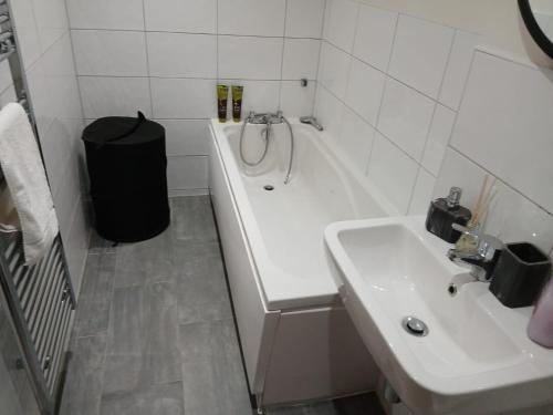 a white bathroom with a sink and a tub and a sink at Cosy family apartment in Bradford