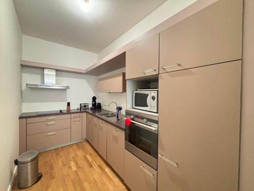 une cuisine avec des armoires blanches et un micro-ondes dans l'établissement Grand appartement T2 proche plage avec wifi, ascenseur et cuisine équipée - FR-1-197-135, à Les Sables-dʼOlonne