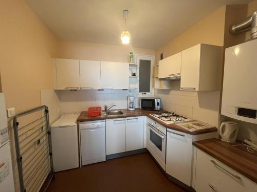 une petite cuisine avec des armoires blanches et un évier dans l'établissement Studio spacieux face à la mer, proche commerces, tout équipé - FR-1-197-265, à Les Sables-dʼOlonne