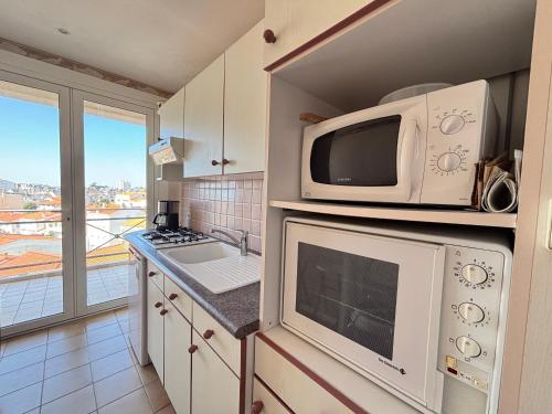 une cuisine avec un micro-ondes et une cuisinière four supérieur dans l'établissement Appartement pour 6 personnes aux Sables-d'Olonne, proche plage, avec balcon - FR-1-197-192, à Les Sables-dʼOlonne