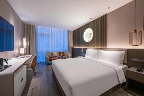 a hotel room with a large white bed and a desk at Orange crystal Beijing Changying Fudi V Center Hotel in Beijing