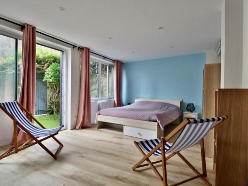 a bedroom with two chairs and a bed and windows at Maison 6 chambres proche plage avec WiFi et salle de jeux - FR-1-197-447 in Les Sables-dʼOlonne