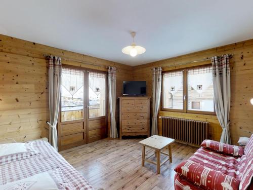 Cette chambre comprend un lit, une télévision et 2 fenêtres. dans l'établissement Appartement confortable 4 pers, proche commerces et pistes, parking inclus - FR-1-467-54, au Grand-Bornand