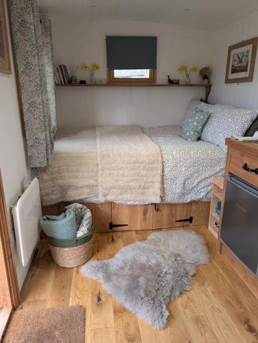a bedroom with a bed and two rugs on the floor at Sycamore Shepherd's Hut in Hamsterley