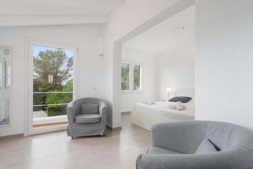 Habitación blanca con cama, silla y sofá en Es Racó -Sa Ràpita-, en Llucmajor