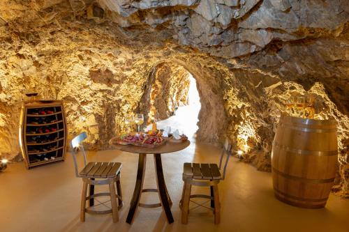 a tasting room in a cave with a table and chairs at Mirabello Bay Luxury Resort in Agios Nikolaos