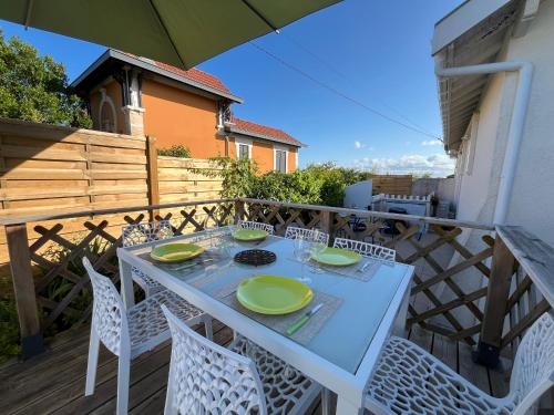 une table blanche avec des assiettes vertes sur un balcon dans l'établissement Maison familiale à Arcachon avec climatisation - FR-1-319-420, à Arcachon