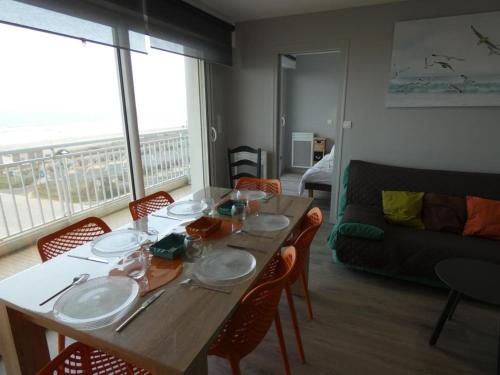 - une salle à manger avec une table, des chaises et un canapé dans l'établissement Notre-Dame-de-Monts - Appartement 2 chambres vue océan, balcon, proche plage & commerces - FR-1-540-120, à Notre-Dame-de-Monts