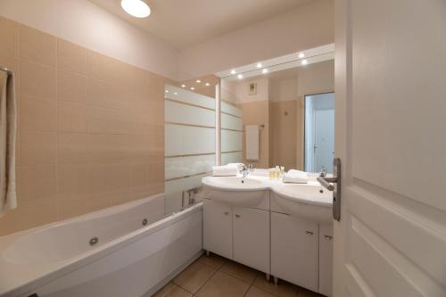 bagno con 2 lavandini, vasca e specchio di Lagrange Vacances - Résidence Jardin Mauresque ad Arcachon