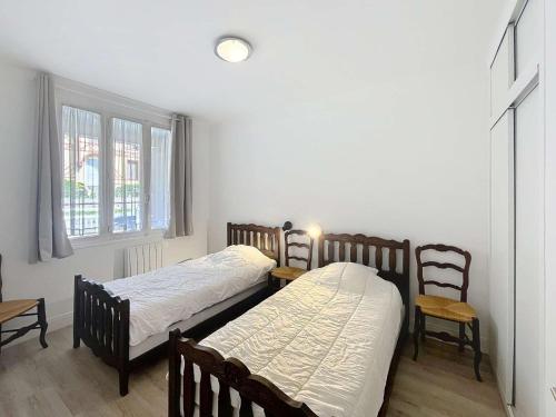 deux lits dans une chambre avec deux chaises et une fenêtre dans l'établissement Maison plain-pied à 150m de la plage avec jardin clos et terrasse - Jullouville - FR-1-361-34, à Jullouville