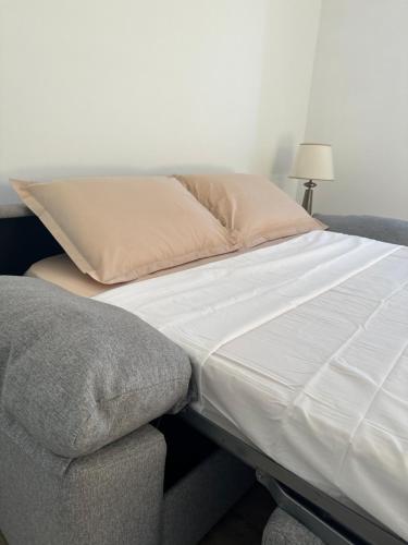 a bed with white sheets and a pillow and a chair at Logement 2 pièces propre et calme in Lieusaint