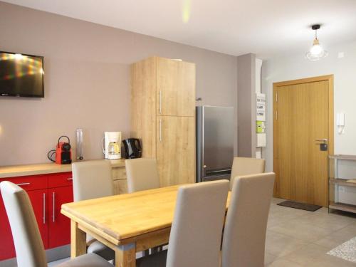 une cuisine avec une table, des chaises et un réfrigérateur dans l'établissement F2 bis au Mont-Dore, 200m du centre et Thermes, parking privé, animaux acceptés, 6 couchages - FR-1-415-69, à Le Mont-Dore